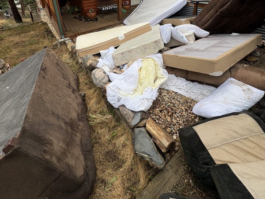 Mattresses, couches and household items piled outside a mountain home before pickup