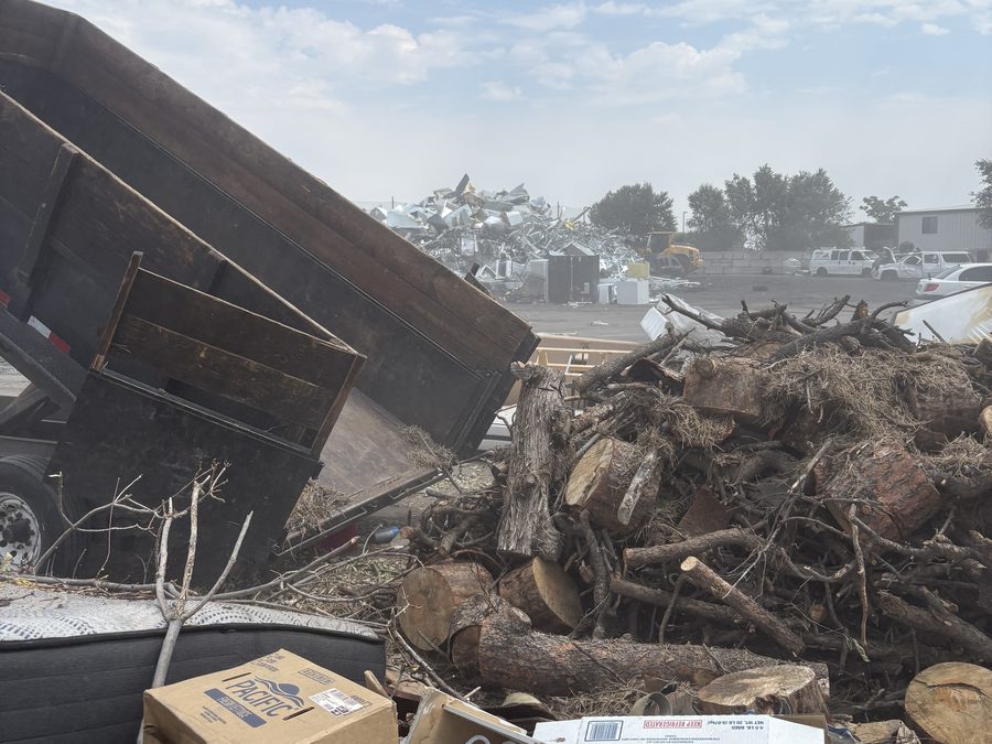 Dump trailer tipped and unloading logs and debris at the transfer yard